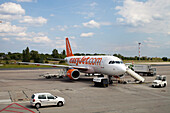 Berlin, Germany, July 21 2009, An EasyJet aircraft is parked on the tarmac at Schönefeld airport in Berlin, with ground crew preparing for passenger boarding.