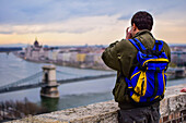 Man taking a photo of Parliament building, Chain Bridge and Danube River in Budapest, Hungary, Europe