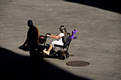 A woman driving a power wheelchair in a square of the city of Segovia.