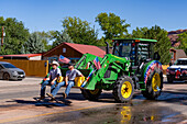 Two young men ride in the scoop of a front-end loader in the Fourth of July Parade on Independence Day in Moab, Utah.