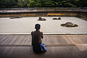 One man meditates at Japanese zen garden, Ryoan-Ji Temple in Kyoto