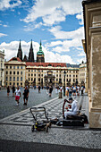 Street musician playing the hurdy-gurdy in a square at Prague Castle complex