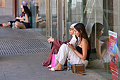 Two girls sitting on the floor in a square of Segovia.