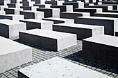 The Memorial to the Murdered Jews of Europe features an expansive arrangement of concrete slabs in Berlin, Germany, under bright sunlight.