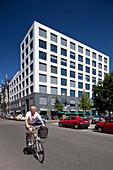 Berlin, Germany, July 27 2009, A cyclist rides past a striking contemporary building on Friedrichstrasse, showcasing Berlin\'s urban landscape and architecture.