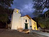 Facade of the Church of Santa Rosa de Lima lit up at night in Purmamarca, Argentina.