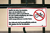 A sign in Berlin instructs against locking bicycles, warning of potential damage to gates and walls, reflecting local regulations.