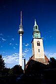 The Fernsehturm stands tall beside the historic Marienkirche in Berlin, showcasing the city\'s blend of modernity and tradition.