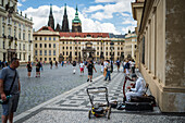 Street musician playing the hurdy-gurdy in a square at Prague Castle complex