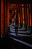 Young caucasian woman exploring Fushimi Inari Taisha temple at night, Kyoto, Japan