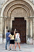 Drei Besucher bewundern die filigranen Details des romanischen Eingangs der Basilika San Isidoro in León, Spanien