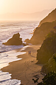 Couple walking on the beach in front of Finca Barlovento at sunset, Tayrona National Park, Colombia