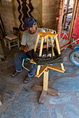 A weaver winds yarn from a wooden vertical-axis swift into a ball for weaving in Seclantas, Argentina in the Calchaqui Valley.