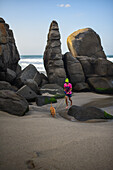 Kid walking his dog on the beach in front of Finca Barlovento, Tayrona National Park, Colombia