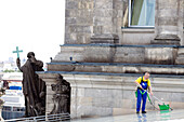 A worker diligently cleans the roof terrace of the Reichstag building in Berlin, ensuring the historic site remains pristine.