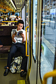 Junger Mann liest ein Buch im Zug, Kyoto