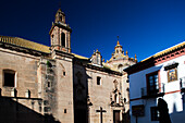 Visitors admire the intricate architecture of the convent of Descalzas against a clear blue sky in the enchanting town of Carmona.