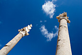 Tall Roman columns rise majestically against a bright blue sky in the Alameda de Hércules, showcasing historical architecture in Seville.