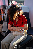 Young woman using smartphone in commuter train, Madrid