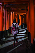 Young caucasian woman exploring Fushimi Inari Taisha temple at night, Kyoto, Japan