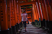 Young caucasian woman exploring Fushimi Inari Taisha temple at night, Kyoto, Japan