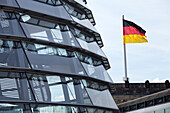 Die ikonische Reichstagskuppel zeigt moderne Architektur, während im Hintergrund stolz die deutsche Flagge über Berlin weht