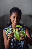 Young afro latin woman gardening and holding an hydroponic plant