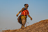 Traditional masked man dancing on a roof of a hut, Tshikapa, Kasai, Democratic Republic of Congo, Africa