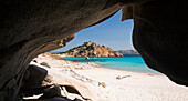 Blick durch den Höhleneingang über das klare türkisfarbene Wasser der Cala Corsara auf die rosafarbene Granitspitze der Punta Rossa Corsara, Insel Spargi, Nationalpark La Maddalena Archipelago, Sassari, Sardinien, Italien, Mittelmeer, Europa