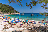 Blick auf eine Strandszene und ein Boot auf dem Meer bei Porto Vathy, Makriammos, Thassos, Ägäisches Meer, Griechische Inseln, Griechenland, Europa