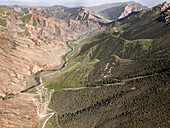 Aerial view of a winding mountain road curves, Kalmak Ashuu Pass, through lush greenery in Kyrgyzstan, Central Asia, Asia