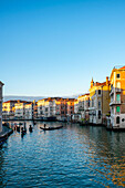 Blick auf bunte Häuser und den Camerlenghi-Palast von der anderen Seite des Canal Grande mit traditionellen Gondeln bei Sonnenuntergang, Venedig, UNESCO-Weltkulturerbe, Venetien, Italien, Europa