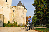 Junge Frau beim Radfahren vor dem Schloss St-Jean, Nogent-le-Rotrou, Parc naturel regional du Perche, Eure-et-Loir, Cengre-Val-de-Loire, Frankreich, Europa