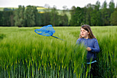 Little girl catching a butterfly in a barley field, Commune of Senantes, Eure-et-Loire department, Centre region, France, Europe