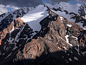 Stunning mountainous landscape of Kyrgyzstan illuminated by fading sunlight and shadowy clouds, Kyrgyzstan, Central Asia, Asia