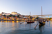 Rabelo-Boote auf dem Fluss Douro mit der Dom-Luis-Brücke in der Abenddämmerung, UNESCO-Welterbe, Porto, Norte, Portugal, Europa