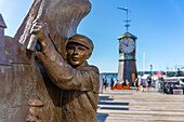 Blick auf Pelle Gruppa Statue und Aker Brygge Uhrenturm im Hintergrund, Aker Brygge, Oslo, Norwegen, Skandinavien, Europa