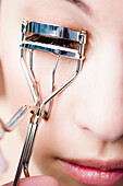 Extreme close up of a woman using an eyelash curler