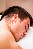 Close up of a man lying on his stomach with his eyes closed