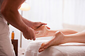 Close up of a masseur hands massaging a woman foot