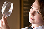 Close up profile of a waitress inspecting a wine glass