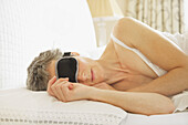 Woman In Bed Wearing Sleep Mask