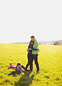 Couple Hugging on Field and Children Lying on Grass