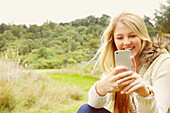 Young Woman in Field Using Smartphone