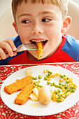 Young Boy Eating Fish fingers and Vegetables