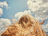 Low angle view teenage girl with long hair below sunny summer sky