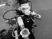 Teenage boy scuba diving and holding sea urchin underwater, Saint Vincent and the Grenadines 