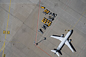 View from above airplane and luggage carts on sunny airport tarmac