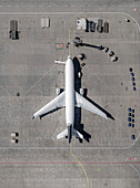 View from above airplane and service vehicles parked on sunny airport tarmac