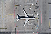 View from above airplane and service vehicles on sunny airport tarmac